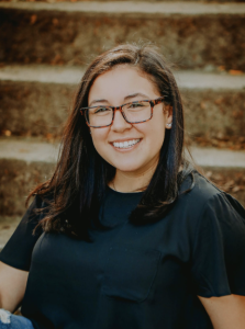 A woman smiles while sitting on concrete stairs. 
